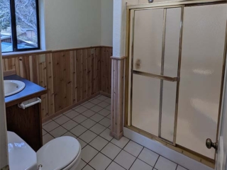 A wide-angle picture of a completed bathroom with beautiful wood paneling.