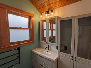A photo of a well-lit bathroom sink, cabinet, and window. There is a lot of natural wood in the design.