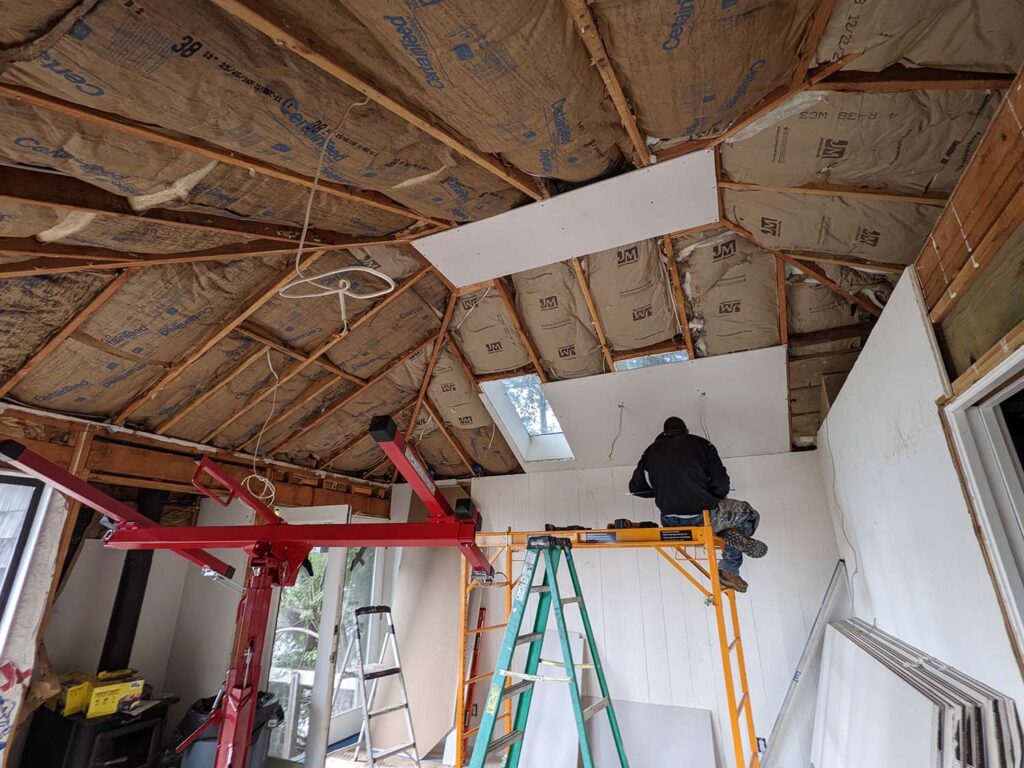 A man sits on some scaffolding and works on a large ceiling that is being rebuilt.