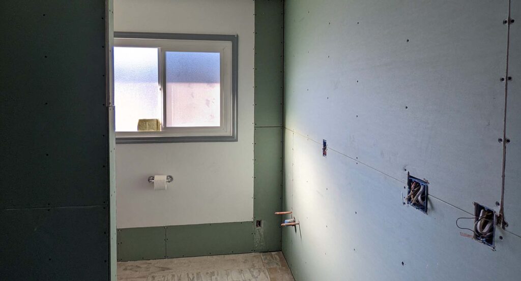 An in-progress picture of a room, with sheetrock and water lines exposed. The room is very clean, with no debris or construction materials around.