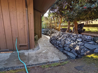 A newly-landscaped rock wall and walkway next to a building.