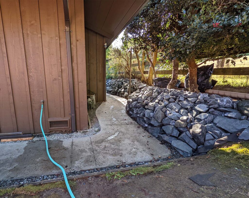 A newly-landscaped rock wall and walkway next to a building.