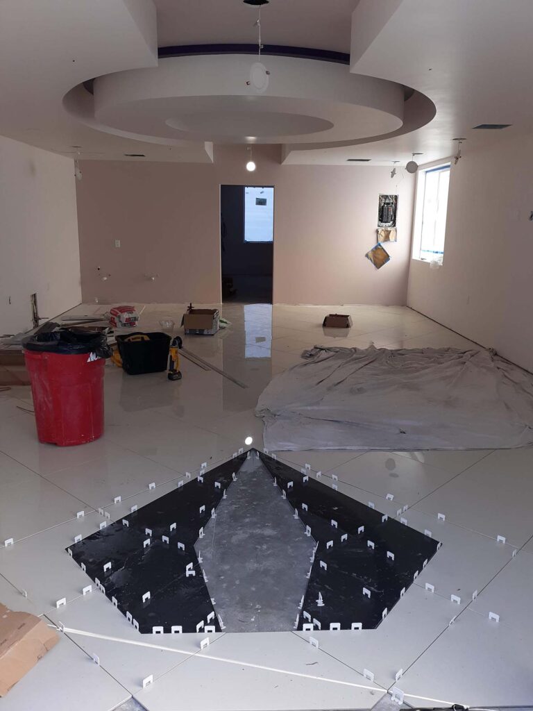 An interior rebuild in progress. There is a large circular feature in the center of the ceiling, and a diamond-shaped feature in the tile in the foreground