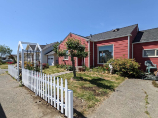 An exterior photo of a freshly-painted house with a newly-built fence and a well-landscaped yard
