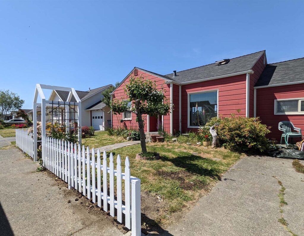 An exterior photo of a freshly-painted house with a newly-built fence and a well-landscaped yard