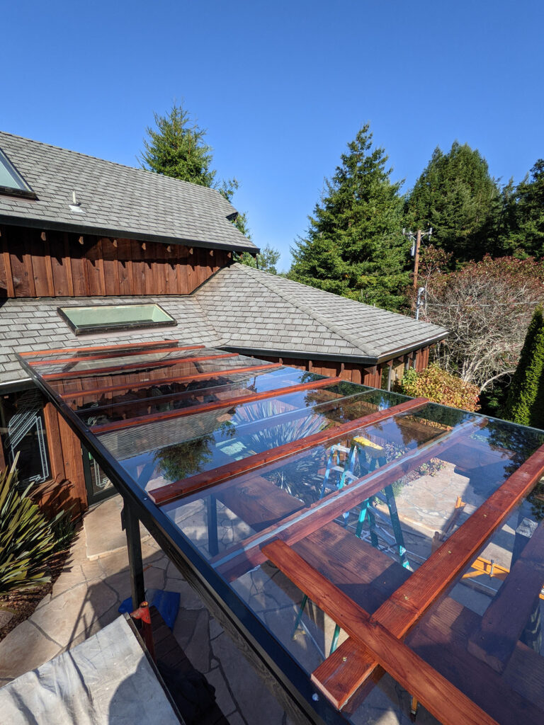 An above shot of a pergola with dark-stained wood and glass