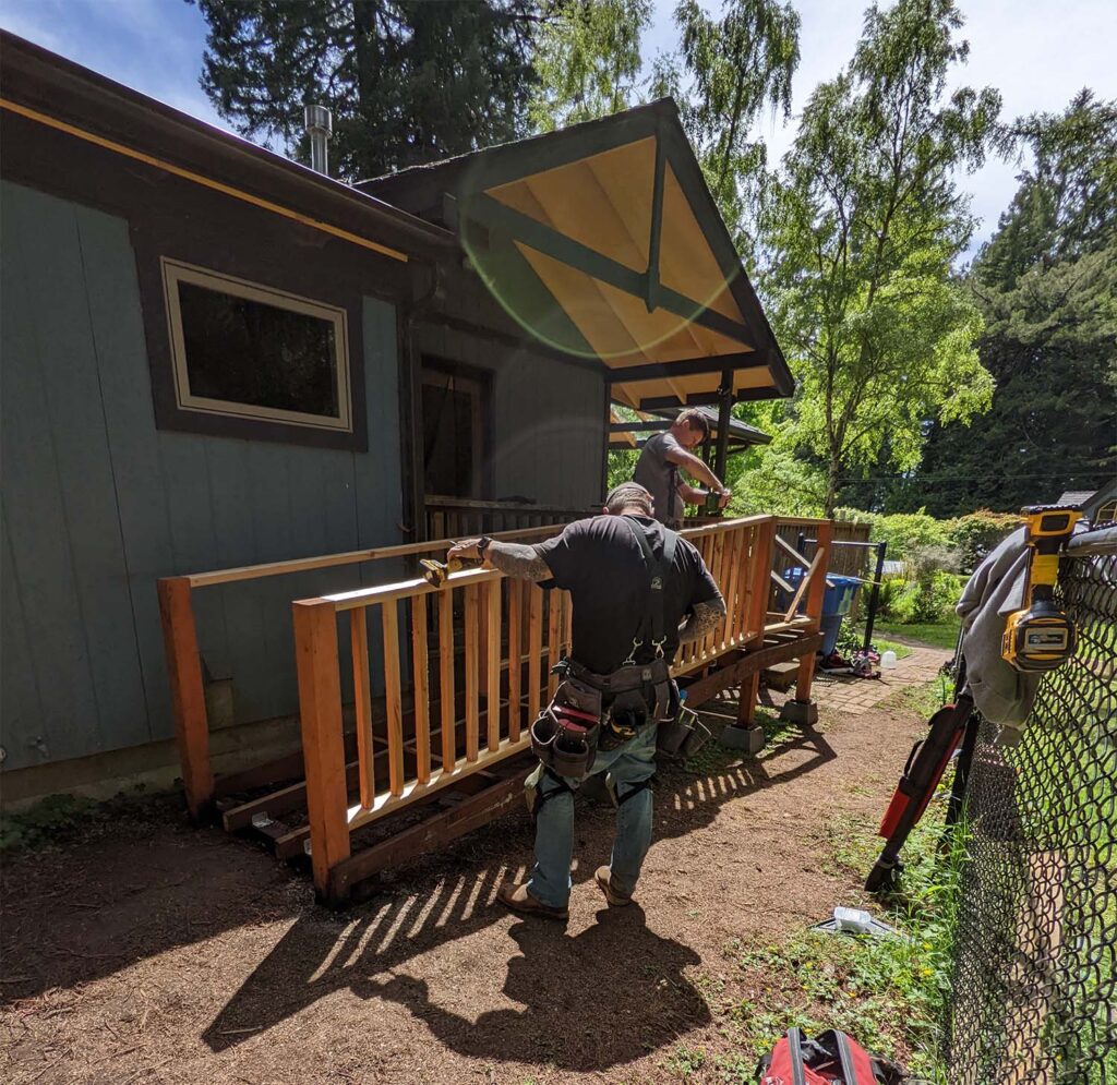 Two men work on a ramp down the front of a house.